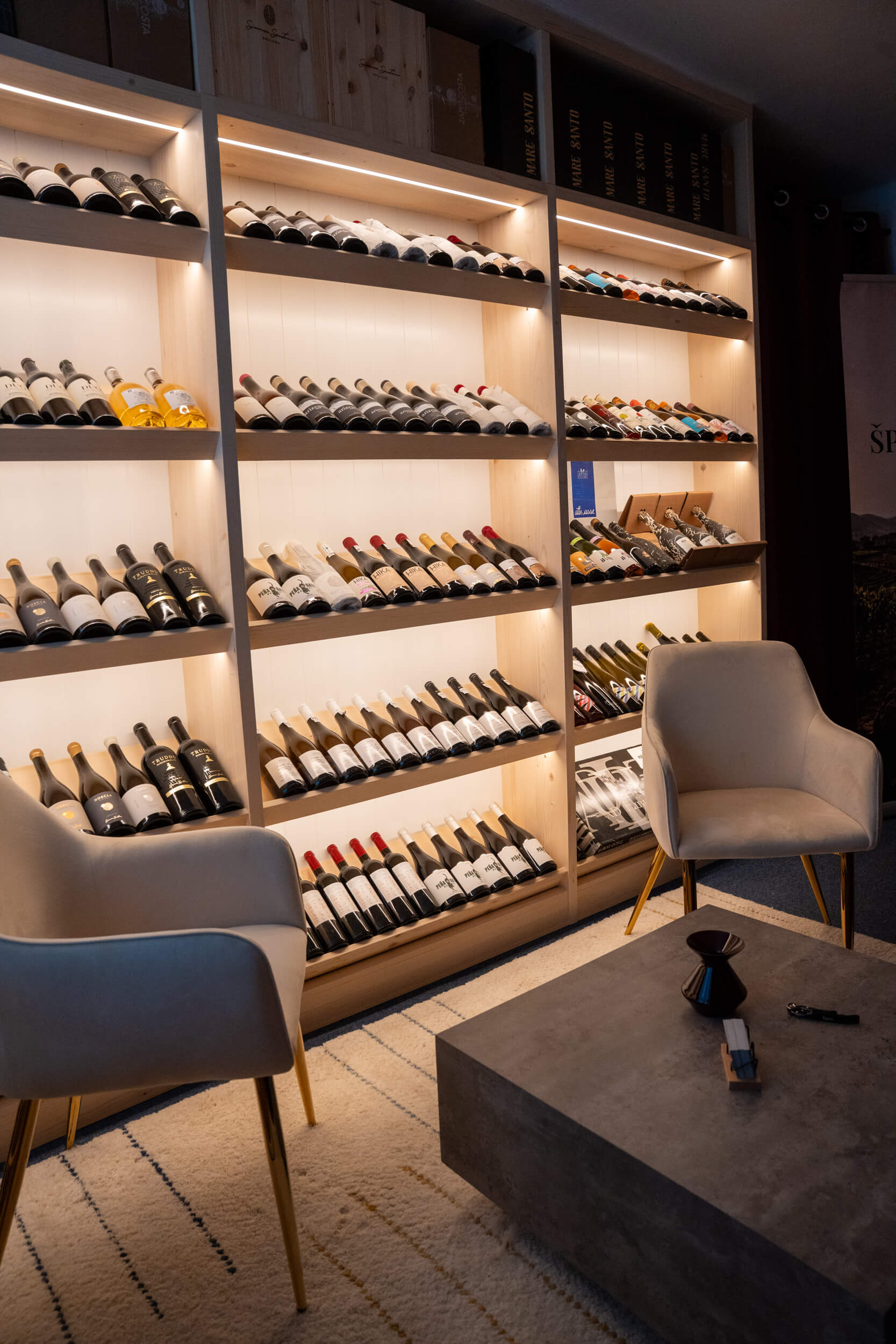 Křesla před policemi s víny v showroomu Sense of Wine